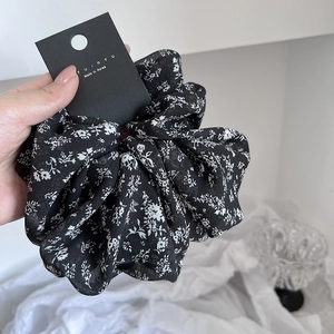 Close-up of large black floral chiffon scrunchie with elegant white flower pattern