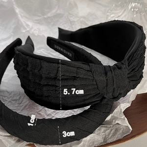 Detail of wide black knotted headband with scrunchie texture and handmade tag