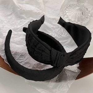 Detailed view of black pleated fabric headbands showing knot design and texture