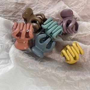 Detailed view of six colorful mini hair claws on a textured cream background