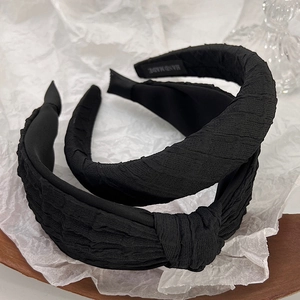 Detail of black pleated fabric headbands with knot design and handmade label