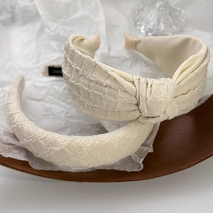 Detailed close-up of cream white seersucker sponge headbands with pleated fabric texture