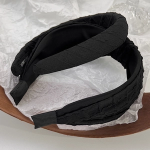 Detail view of handmade black pleated headband with woven label and ribbed fabric finish