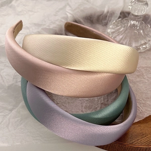 Detailed macro view of four pastel thickened sponge headbands with soft satin fabric texture