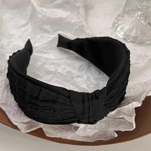 Detail of black sponge headband featuring pleated texture and elegant top knot knotting