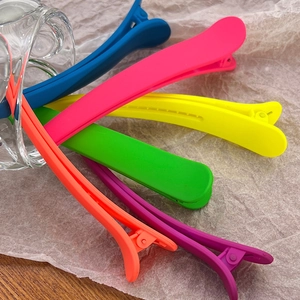Close-up of matte candy-colored hair clips set on textured background with glassware