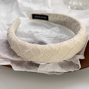 Detail of beige sponge headband with wavy fabric texture and Hand Made inner label