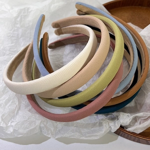 Serre-têtes en tissu coloré empilés sur fond blanc avec détails de texture de tissu fin