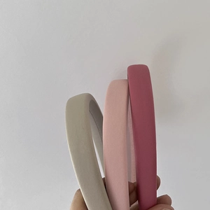 Three colorful padded sponge headbands in grey pink and rose colors shown in hand