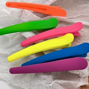 Detailed view of matte neon hair clips in vibrant orange, green, pink, and blue colors