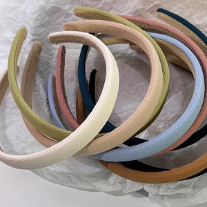 Détail de serre-têtes en tissu coloré aux tons pastels élégants sur un fond blanc texturé