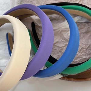 Close-up of thick sponge headbands in white, purple, blue, and green fabric textures