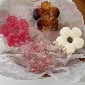 Detail of flower hair claws in four colors on white paper with a high gloss finish