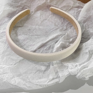 Détail du serre-tête en tissu crème montrant la texture fine et la doublure interne