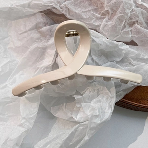 Détail de la pince à cheveux en résine crème avec design croisé et ressort métallique robuste