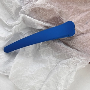 Macro detail of Klein blue matte hair clip on textured paper background for hairstyling
