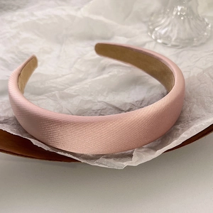 Detail of pink padded sponge headband with satin texture and non-slip inner lining