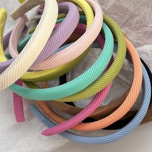Détail de serre-têtes en tissu côtelé aux couleurs macaron sur un fond blanc texturé