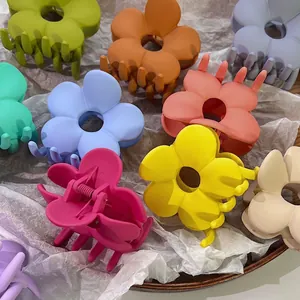 Matte Haarklammern in Blumenform in verschiedenen Macaron-Farben auf Textur