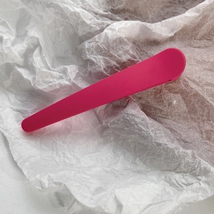 Detail shot of a matte magenta long hair clip on a textured white paper background