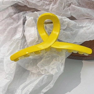 Vue détaillée d'une pince à cheveux jaune vif avec finition brillante et ressort robuste