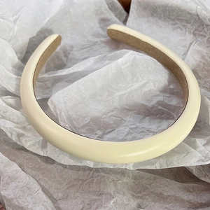 Close-up of cream white padded headband with faux leather texture and soft velvet lining