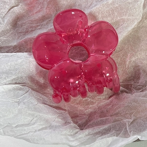 Detail view of a translucent rose red flower hair claw clip on a white background