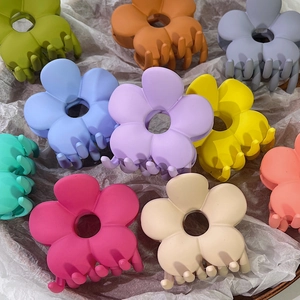 Matte Blumen-Haarklammern in verschiedenen Bonbonfarben auf strukturiertem Papier