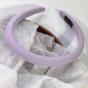 Gros plan d'un serre-tête rembourré violet avec étiquette faite main sur tissu doux