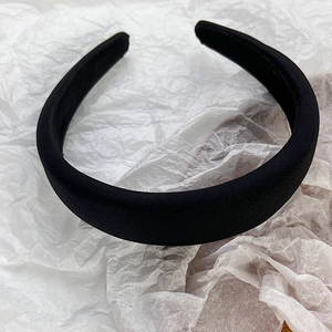 Close-up of thick black padded headband with satin finish on white textured paper
