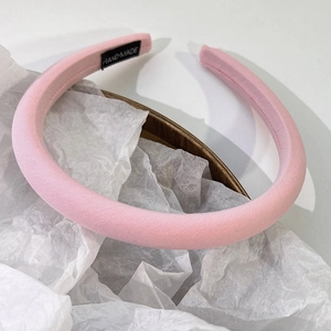 Détail d'un serre-tête rembourré rose fait main avec tissu texturé et étiquette tissée
