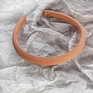 Détail d'un serre-tête en tissu sergé rose orangé montrant l'éclat et les coutures
