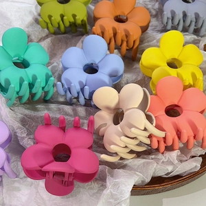 Makro-Detail von verschiedenen matten Blumen-Haarklammern in Pastellfarben auf Holztablett
