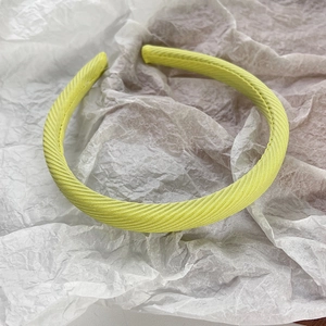 Détail d'un serre-tête en tissu jaune vif avec texture sergé sur fond blanc pur
