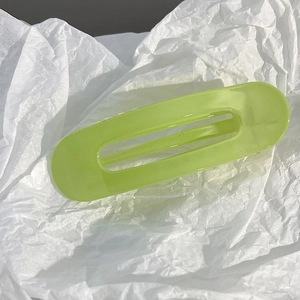 Détail d'une pince à cheveux vert clair translucide avec un design ajouré sur papier