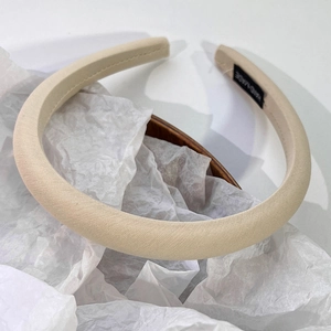 Détail d'un serre-tête rembourré en tissu sergé beige avec étiquette faite à la main