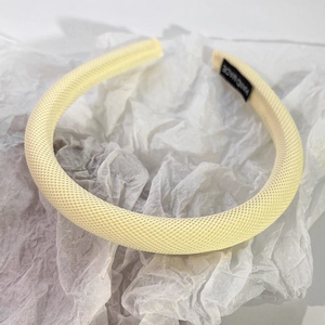 Détail d'un serre-tête éponge beige fait main avec tissu en maille texturée et étiquette