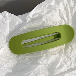 Gros plan sur une pince à cheveux rectangulaire vert herbe mat sur papier blanc