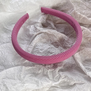Vue détaillée d'un serre-tête en tissu côtelé rose foncé sur fond de papier blanc décoratif