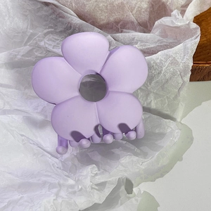Nahaufnahme einer matten violetten Blumen-Haarklammer auf weißem Papierhintergrund