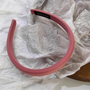 Detail showing the pink fabric headband with a black handmade woven label on the inner side