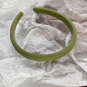 Détail d'un serre-tête en tissu sergé vert olive avec texture douce sur fond de papier