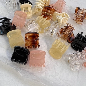 Mini hair claw clips in various colors arranged on white textured fabric background