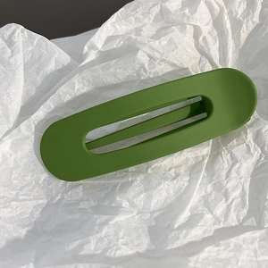 Gros plan sur une pince à cheveux ovale creuse vert herbe mat avec ressort en métal