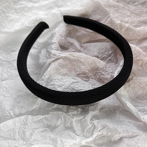 Vue détaillée de la texture du tissu sergé noir sur un serre-tête en éponge minimaliste