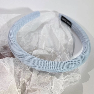 Gros plan du serre-tête bleu clair en tissu avec étiquette Hand Made sur papier froissé