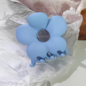 Detailaufnahme einer matt himmelblauen Blumen-Haarklammer auf weißem strukturiertem Grund