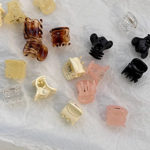 Close-up of assorted mini claw clips in amber, black, cream, and pink on white background