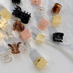 Close-up of mini resin hair claws in assorted colors including amber and cream white
