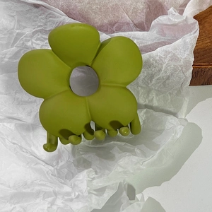 Nahaufnahme der mattgrünen Blumen-Haarklammer auf weißem, zerknittertem Papier